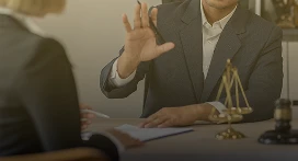 Two people in business attire sit at a table. One raises a hand while discussing documents, with a small scale of justice and a gavel on the table, suggesting a legal or property management consultation with Lyon Property Group in Rhode Island and Eastern Connecticut.