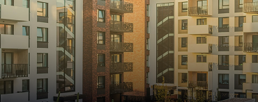 Modern apartment buildings with multiple floors, balconies, and a mix of white and brick exteriors, viewed in soft, warm sunlight—expertly managed by Lyon Property Group in Rhode Island and Eastern Connecticut.